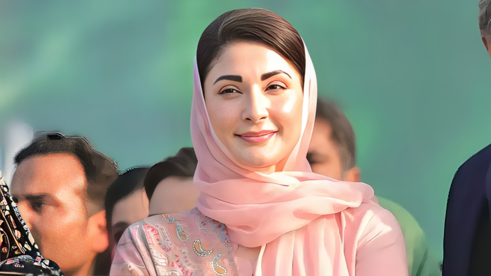 Maryam Nawaz smiling during a public appearance, wearing a pink scarf and looking confidently into the camera.