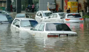 Flooded streets in Karachi with cars submerged in water after heavy rainfall, as Malir and Lyari rivers overflow and evacuations continue.
