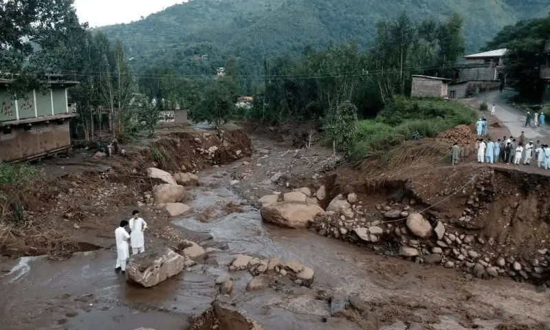 Severe flood damage in KP, showing damaged roads and infrastructure with residents assessing the aftermath of the natural disaster.
