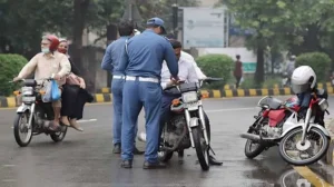 Two motorcyclists riding through the streets of Multan with one wearing a mask and sunglasses