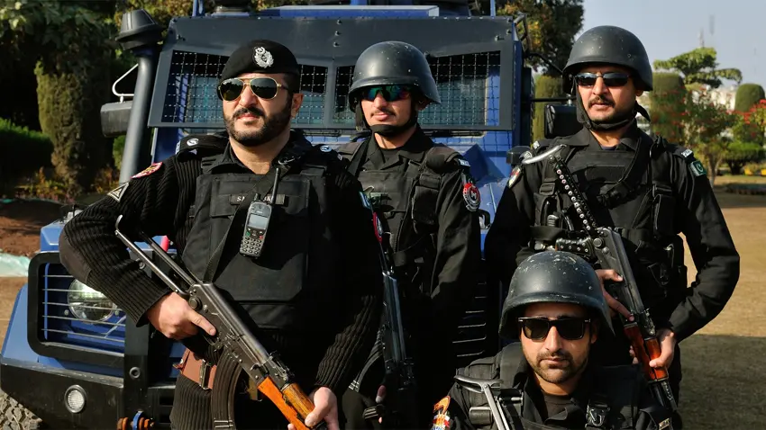 Armed police officers in Dera Ismail Khan standing alert in front of an armored vehicle during an anti-terror operation