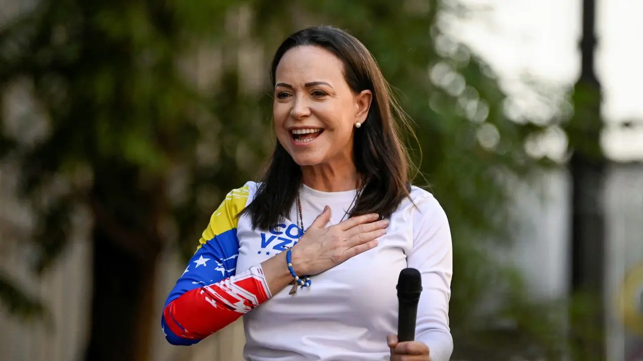 Maria Corina Machado smiling during a public event after winning the 2025 Nobel Peace Prize, wearing a Venezuelan flag-themed outfit and holding a microphone
