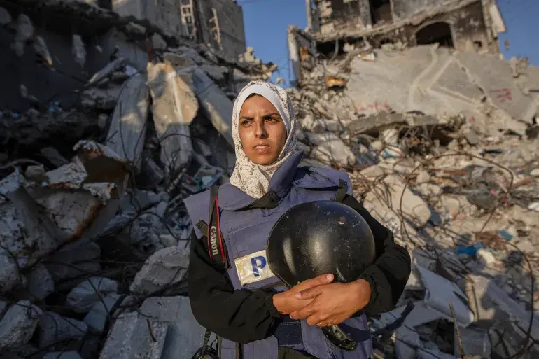 Maryam Abu Daqa, Palestinian journalist in protective vest, standing amid Gaza ruins — nominated for the 2025 World Press Freedom Heroes Award