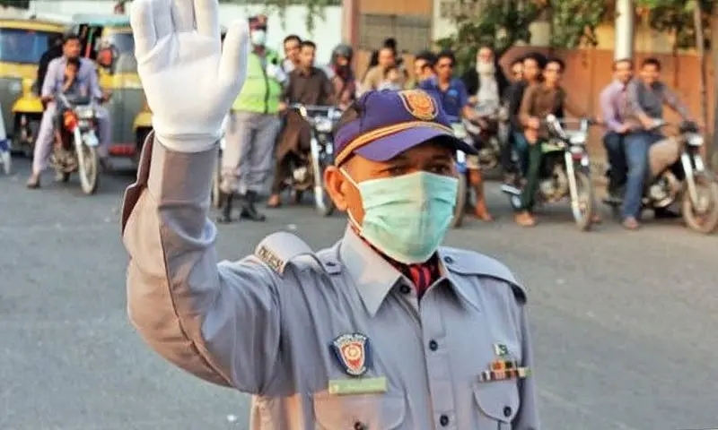 Punjab Police traffic warden wearing a face mask directs vehicles during traffic enforcement operation in Lahore, Pakistan