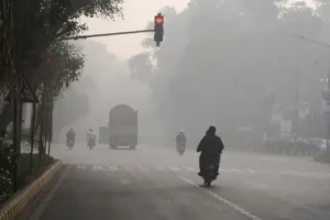 Dense smog covering a road in Lahore as motorcyclists ride through poor visibility, illustrating rising Smog in Pakistan Winter conditions