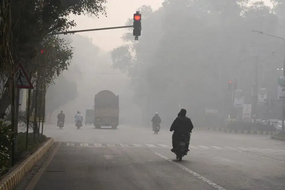 Dense smog covering a road in Lahore as motorcyclists ride through poor visibility, illustrating rising Smog in Pakistan Winter conditions