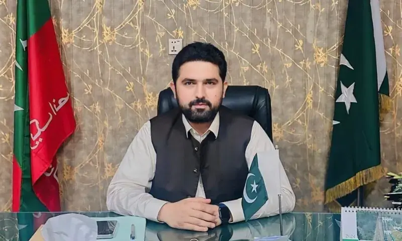 Sohail Afridi, newly appointed Chief Minister of Khyber Pakhtunkhwa, seated at his office with PTI and Pakistan flags.