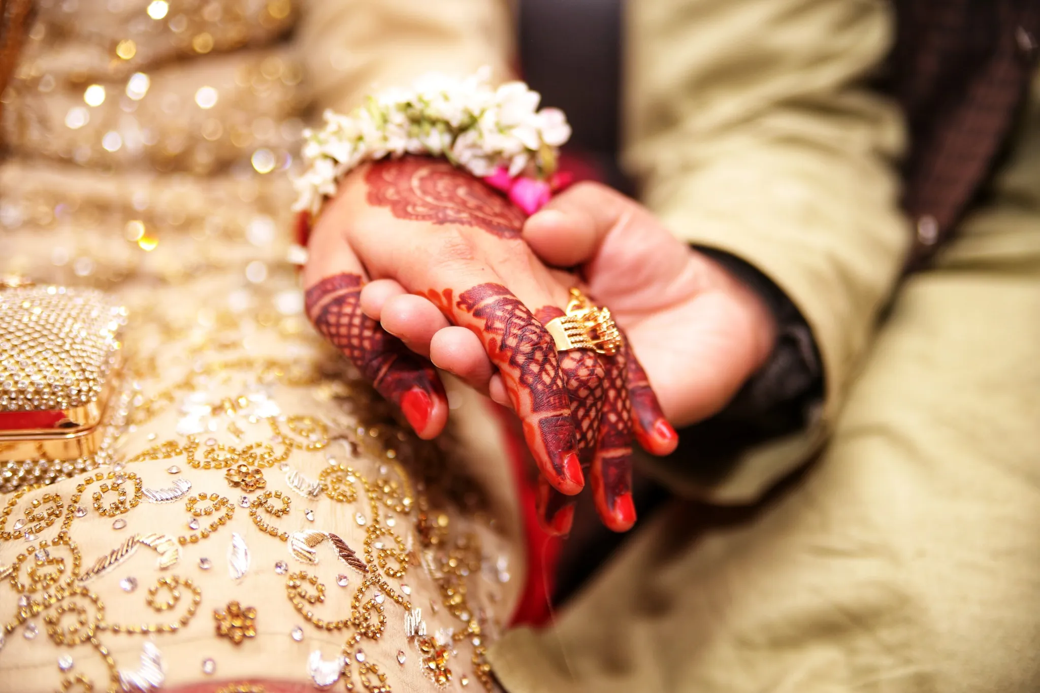Close-up of a bride and groom holding hands during a traditional ceremony