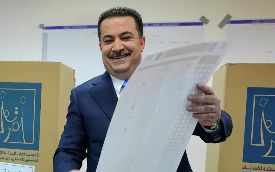 Iraqi Prime Minister Mohammed Shia al-Sudani holding an election ballot after winning the majority seats
