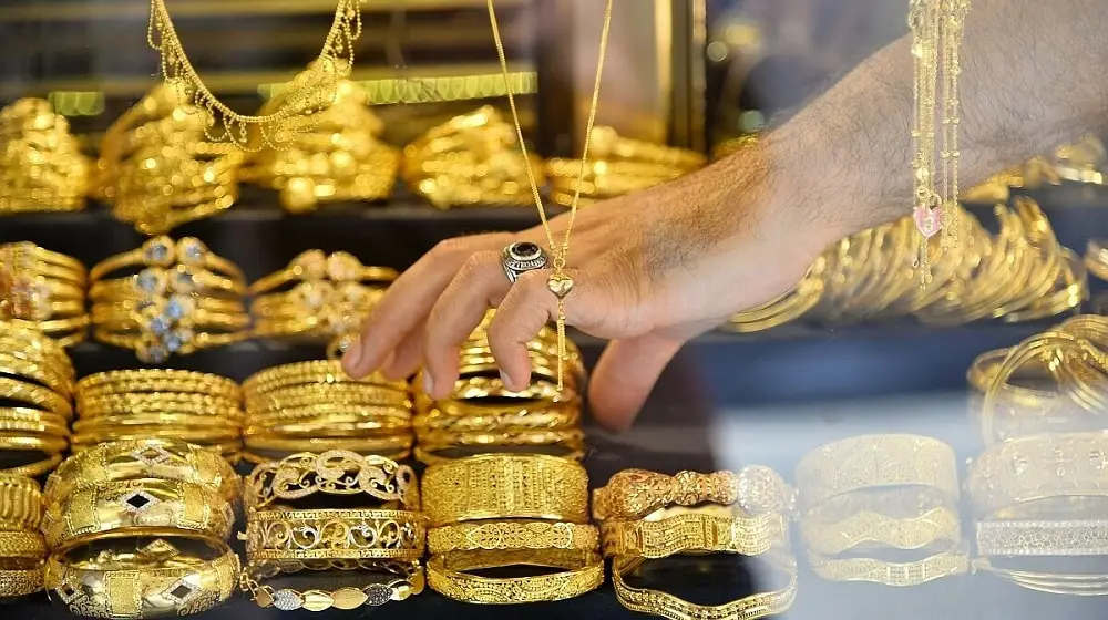 Hand selecting gold jewelry from a shop display in Pakistan