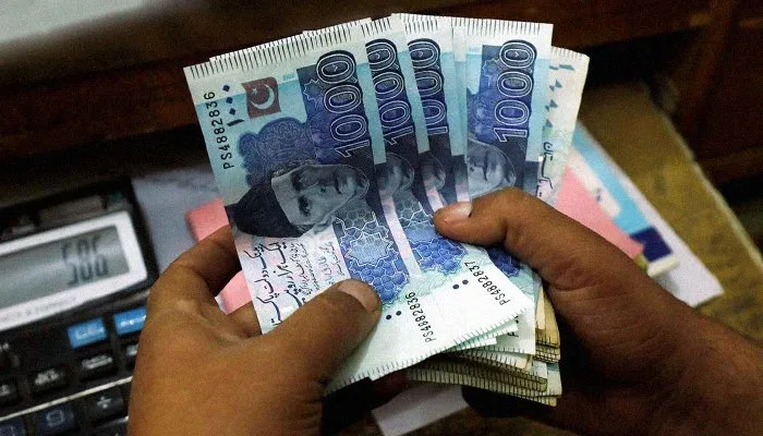 A person counting Pakistani currency notes symbolizing Punjab’s Rs. 10,000 reward for reporting undocumented Afghan residents.
