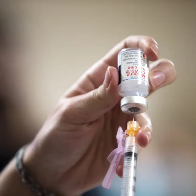 Close-up of a healthcare worker preparing a vaccine dose with a syringe