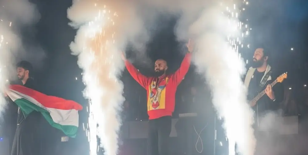 Talha Anjum performing on stage in Nepal as a band member waves the Indian flag, symbolizing unity and peace through music.
