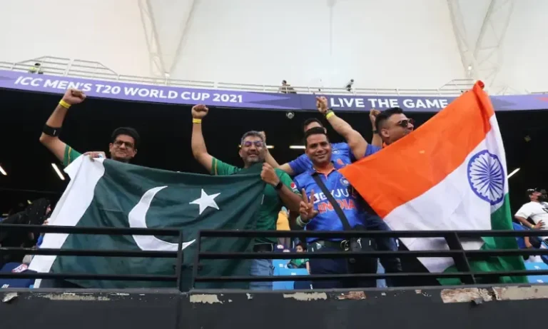 Indian and Pakistani cricket fans holding national flags during a T20 World Cup match in a packed stadium