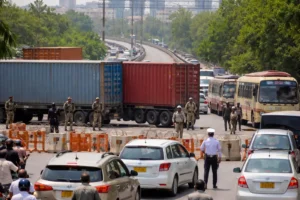 Security personnel and containers blocking road during Karachi road closures with heavy traffic congestion