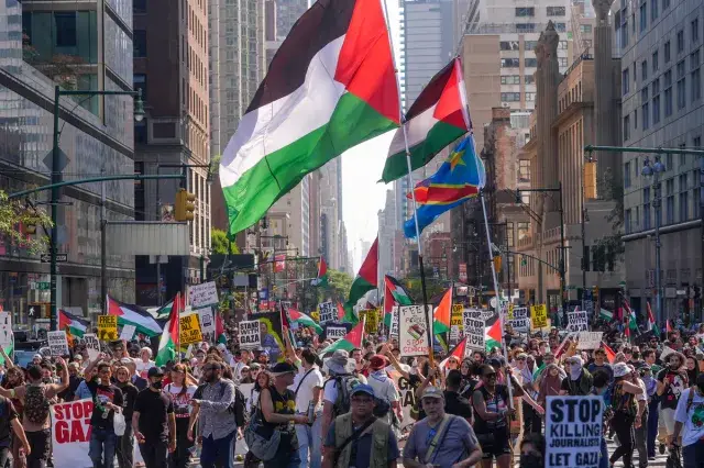 Large Palestine protest march in New York City with people holding flags and banners calling for Gaza ceasefire