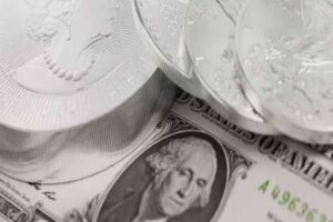 Close-up of US dollar banknotes and silver coins, illustrating the surge in global prediction markets ahead of the US-Iran dialogue.