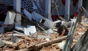 Aftermath of earthquake destruction in Indonesia showing collapsed buildings and debris, with a person inspecting rubble, highlighting indonesia tsunami warning.