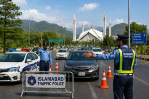 "Islamabad Traffic Police officers managing traffic at a checkpoint with a view of Faisal Mosque and mountains in the background."