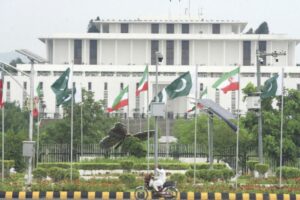 A man riding a motorcycle past the President House in Islamabad, decorated with Pakistani and Iranian flags ahead of the US-Iran peace negotiations.