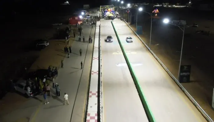 Floodlit racing track hosting Karachi Night Races with cars competing during a nighttime motorsports event