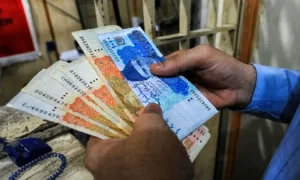 A person counting Pakistani rupee notes during a financial review related to audit irregularities in federal departments.