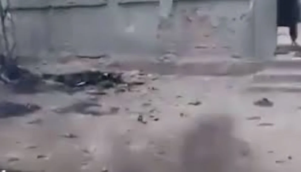 Blurry view of damaged ground covered with rubble and debris near a concrete wall and steps, showing destruction or poor conditions in an outdoor area