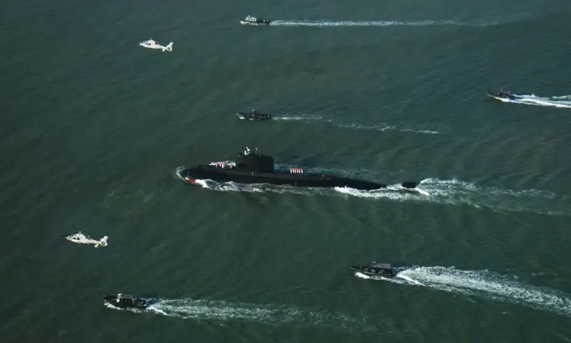 Pakistan Navy Hangor submarine sailing near Karachi with naval boats and helicopters during a ceremonial welcome
