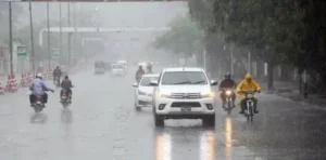 Vehicles and motorcyclists traveling on a rain-soaked road during Karachi Rain as light showers improve weather conditions