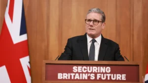 Keir Starmer speaking at a podium in front of a UK flag amid growing resignation pressure.