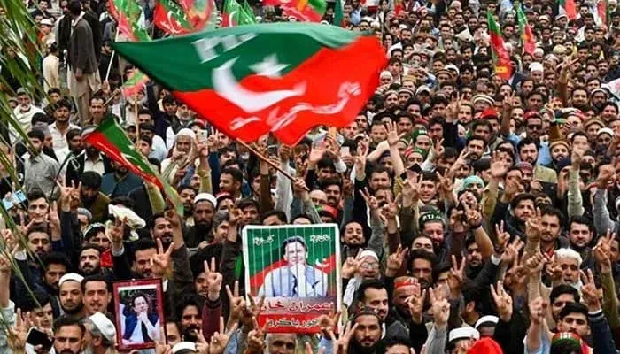 PTI supporters holding party flags during a political rally as discussions over PTI Resignations continue