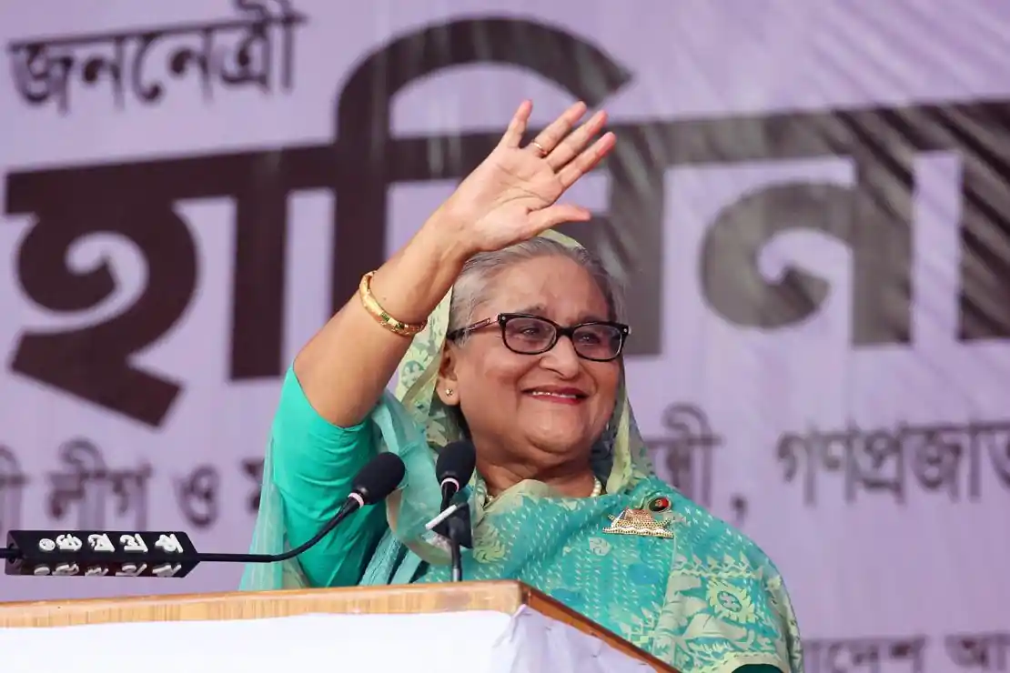 Sheikh Hasina waves during a public speech as the former Bangladesh prime minister discusses her planned return to Bangladesh.