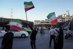 People waving Iranian flags in Tehran after the announcement of the US Iran ceasefire agreement and reopening of the Strait of Hormuz.