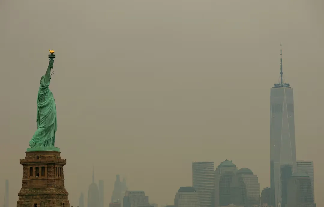 The Statue of Liberty and the New York City skyline covered by Canada Wildfire Smoke, reducing visibility and creating hazardous air quality.