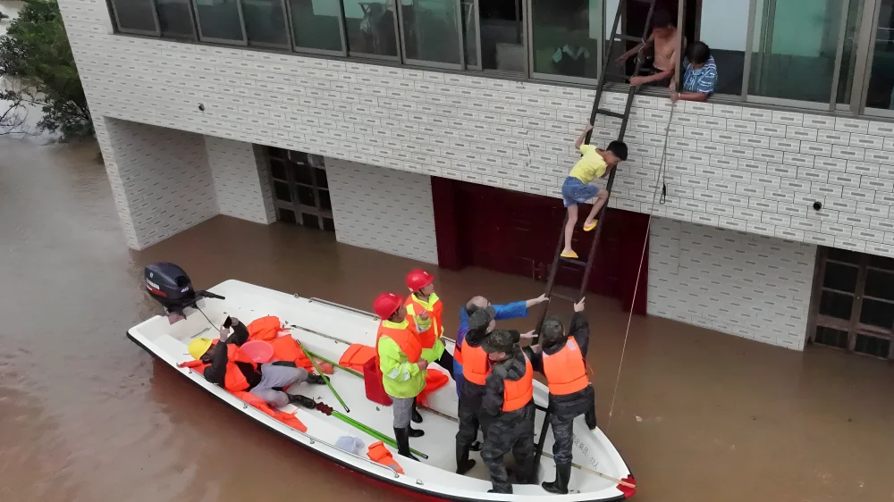 Rescue workers evacuate residents by boat during China Storms after severe flooding submerged residential areas.