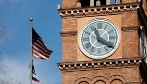 Daylight Saving Time debate highlighted by a clock tower and the US flag as lawmakers consider ending twice yearly clock changes.