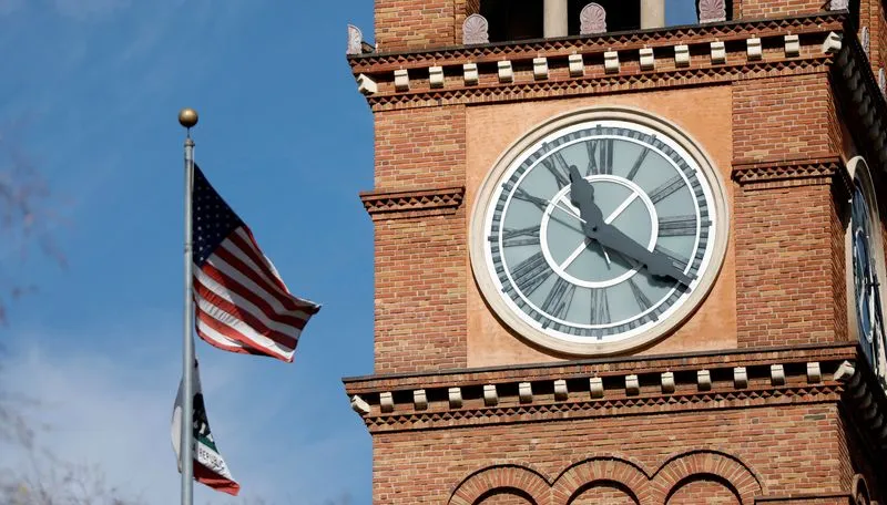 Daylight Saving Time debate highlighted by a clock tower and the US flag as lawmakers consider ending twice yearly clock changes.