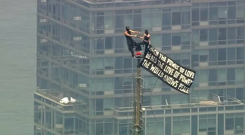 Russian couple performing Empire Proposal stunt on top of the Empire State Building with a peace banner