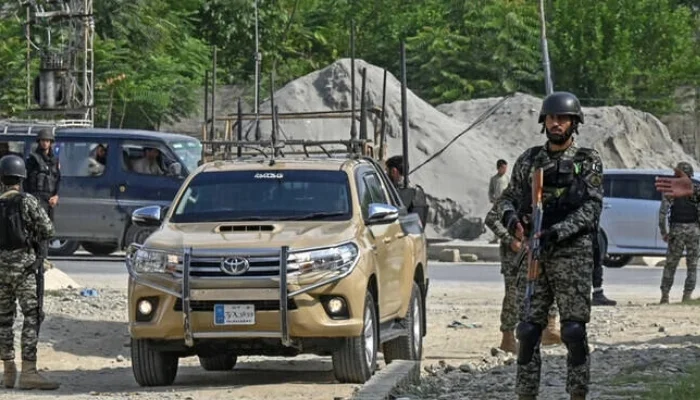 Pakistan security forces standing guard near a military vehicle during a security operation at a roadside checkpoint.