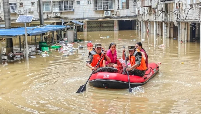 Rescue workers evacuate residents by inflatable boat through flooded streets during China Storms caused by severe rainfall and flooding.