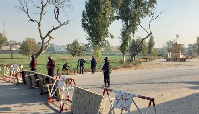 Punjab Police personnel deployed at a security checkpoint with road barriers during heightened security measures in Pakistan.