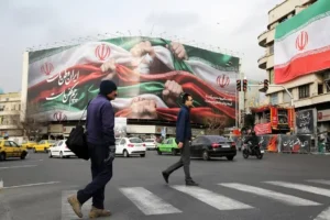 People walk past an Iranian billboard in Tehran as Iran Sanctions intensify following new US financial restrictions.