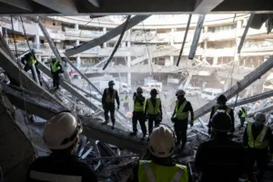 Rescue workers in safety gear searching rubble inside a collapsed shopping mall after the Japan earthquake in Kumamoto