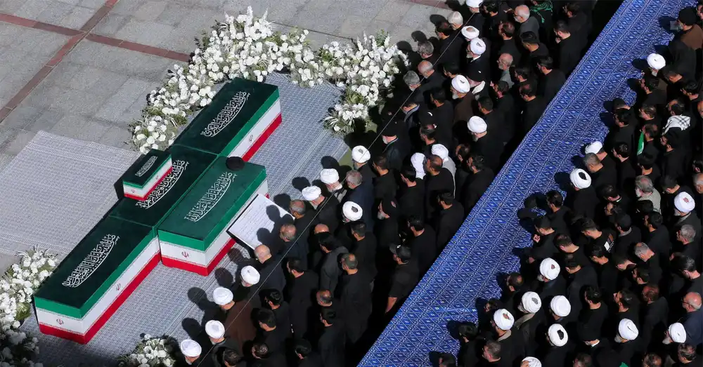 Mourners gather during the Khamenei funeral prayer in Tehran as family members stand beside the coffins.