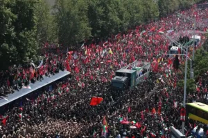 Thousands of mourners gather during the Khamenei funeral procession in Tehran, waving Iranian flags as the funeral convoy passes through the city.