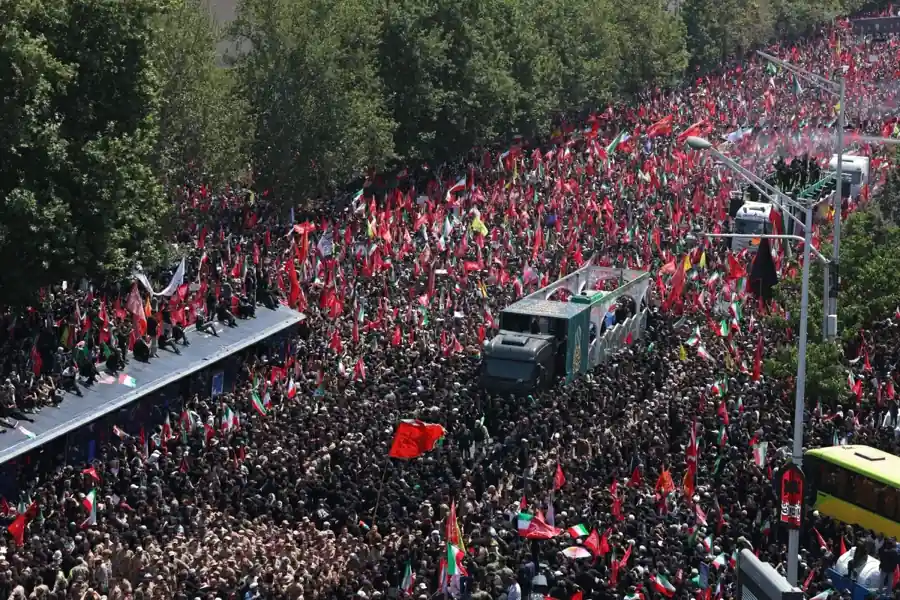 Thousands of mourners gather during the Khamenei funeral procession in Tehran, waving Iranian flags as the funeral convoy passes through the city.