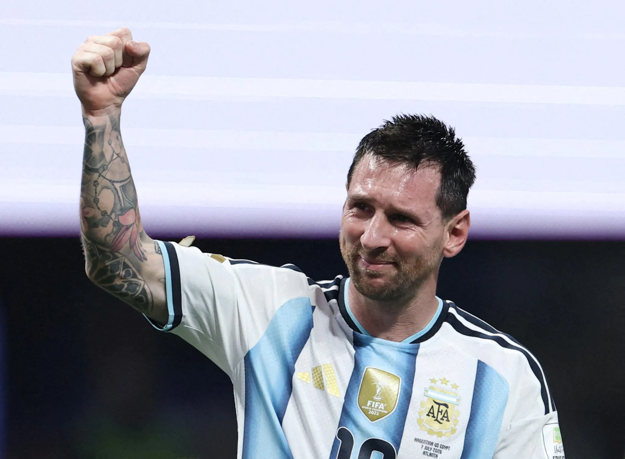 Lionel Messi celebrates with a raised fist while wearing the Argentina national football team jersey after a match.
