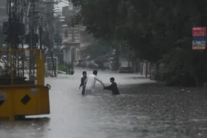People walk through floodwater during heavy rainfall as the Monsoon Flood Alert remains in effect across Pakistan.