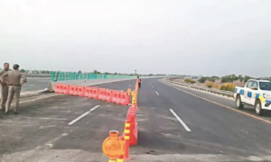Newly constructed expressway with traffic barriers, road safety cones, police vehicles, and officers managing traffic on a multi-lane highway.