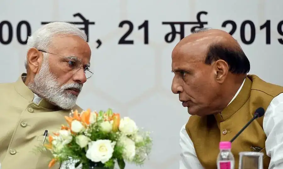 Rajnath Singh speaks with Indian Prime Minister Narendra Modi during an official government meeting amid political controversy.